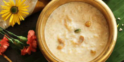 Punjabi-style rice kheer served in a traditional bronze bowl with nuts on top.
